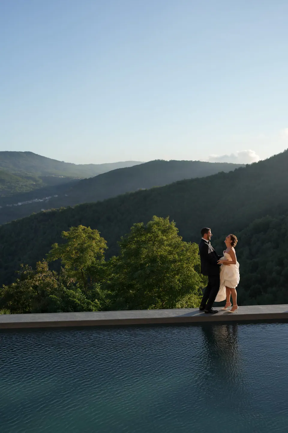 Sposi sul bordo della piscina a sfioro, le valli del Cilento sotto di loro.