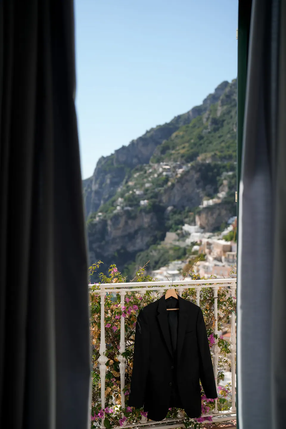 Groom's jacket hanging on the balcony railing, Positano behind it.