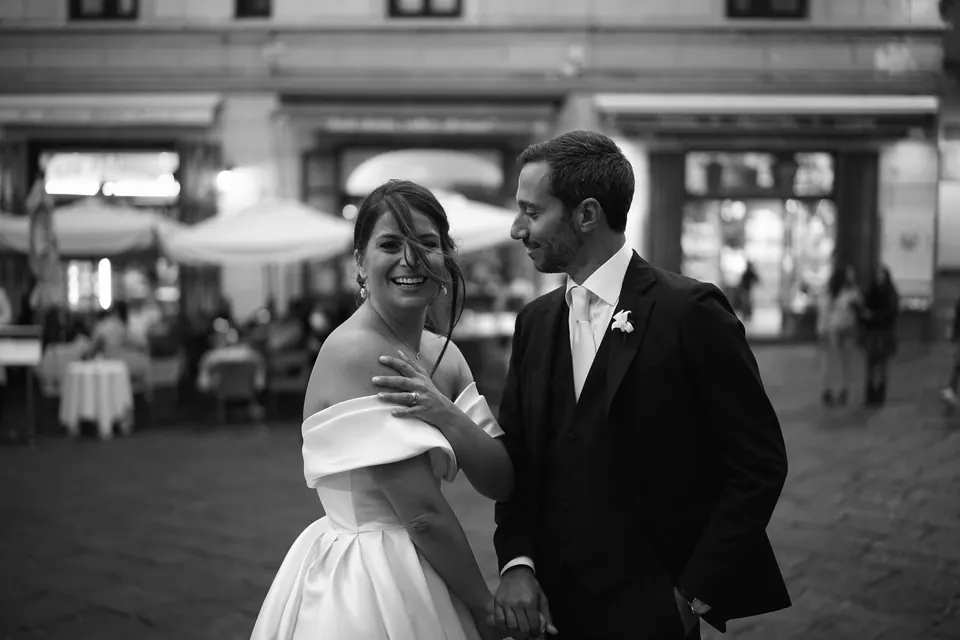 Black and white photo of the couple laughing in the piazza of Amalfi in the evening.