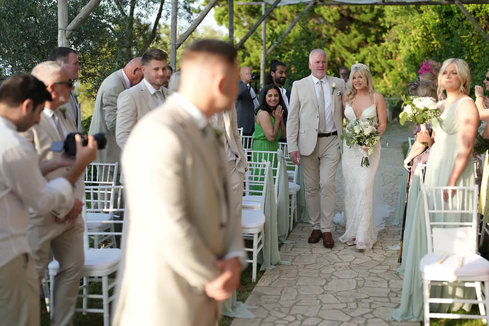 Lo sposo guarda la sposa che arriva lungo la navata con il papà