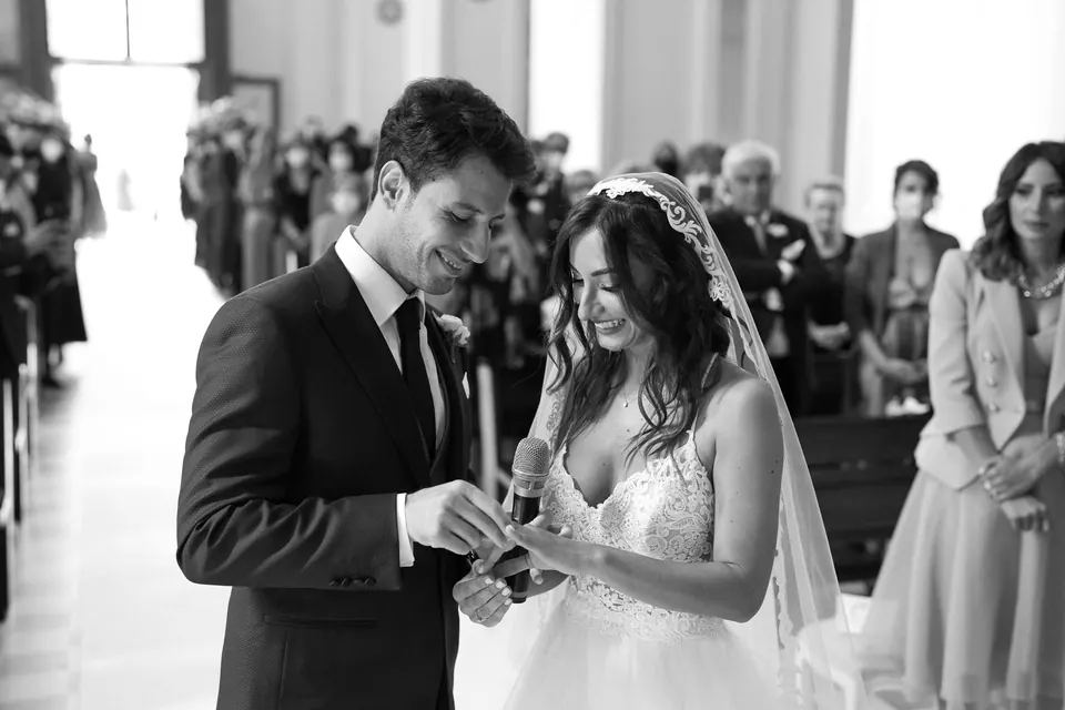 Foto in bianco e nero dello scambio degli anelli durante la cerimonia.
