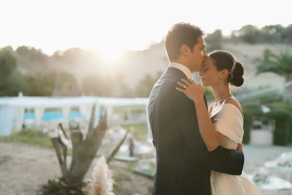 Bacio degli sposi in giardino al tramonto.