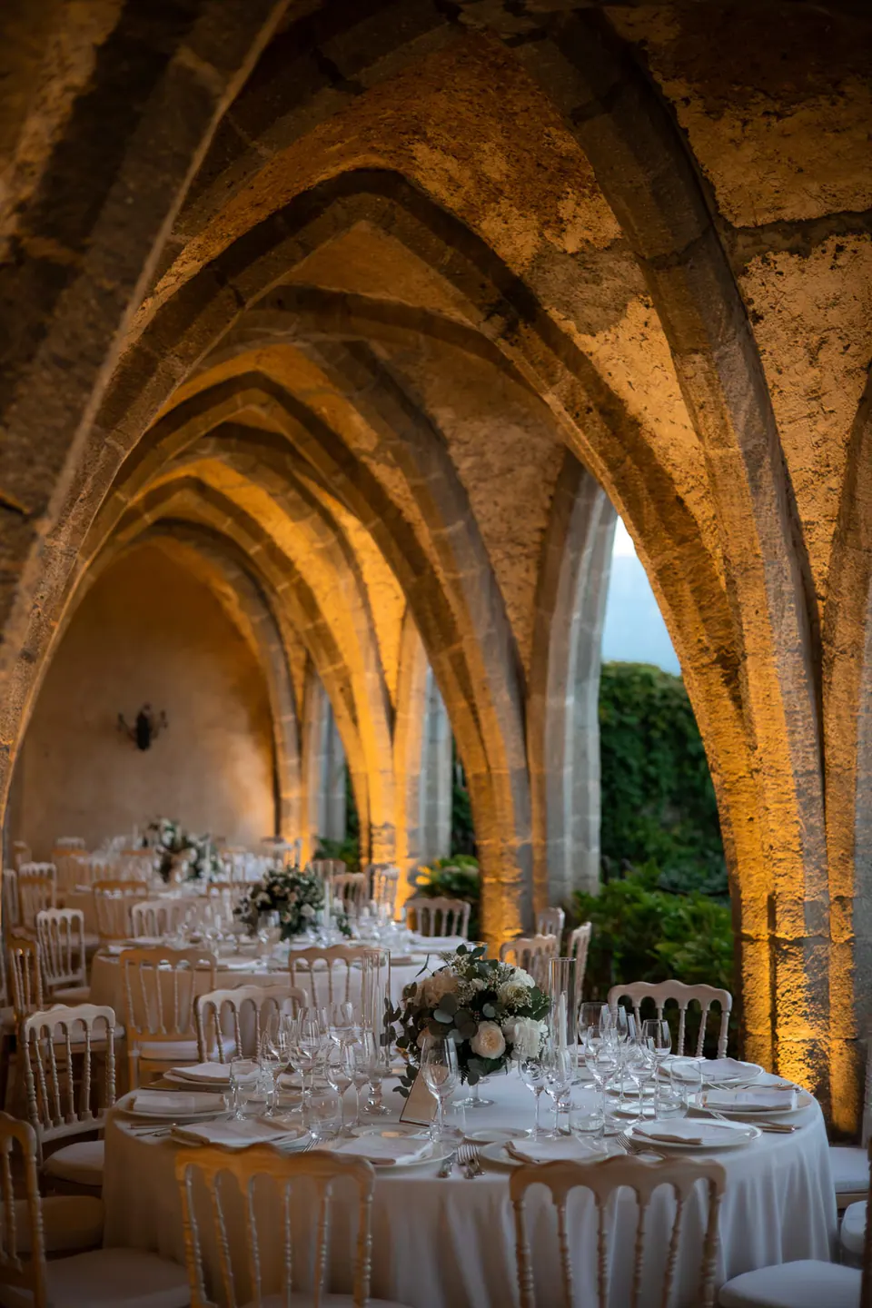 Dinner tables set beneath the Gothic arches of the Villa Cimbrone crypt, warm evening light.