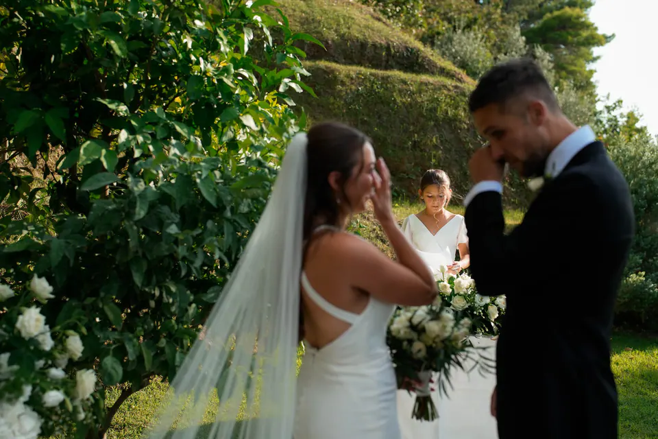 Groom overcome with emotion as the bride smiles beside him at the ceremony.