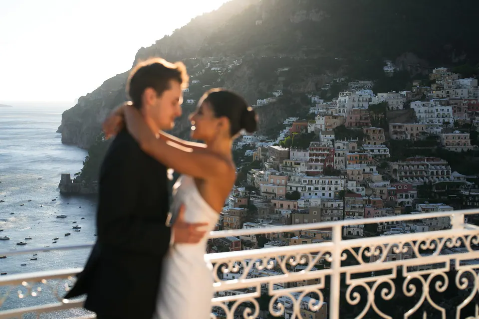 Bride and groom embracing at the railing above Positano.