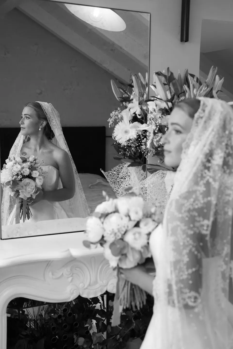 Schwarzweißfoto der Braut und ihres Spiegelbilds, den Strauß in der Hand.