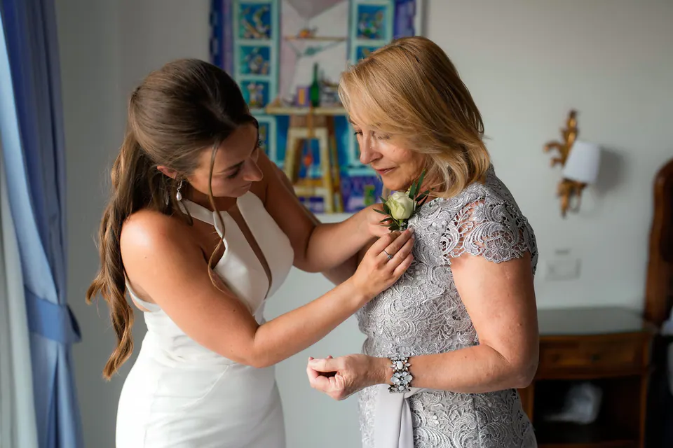 Bride pinning a flower on her mother's dress before the ceremony.