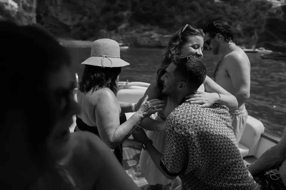 Black and white photo of friends cheering the couple on the boat after the yes.