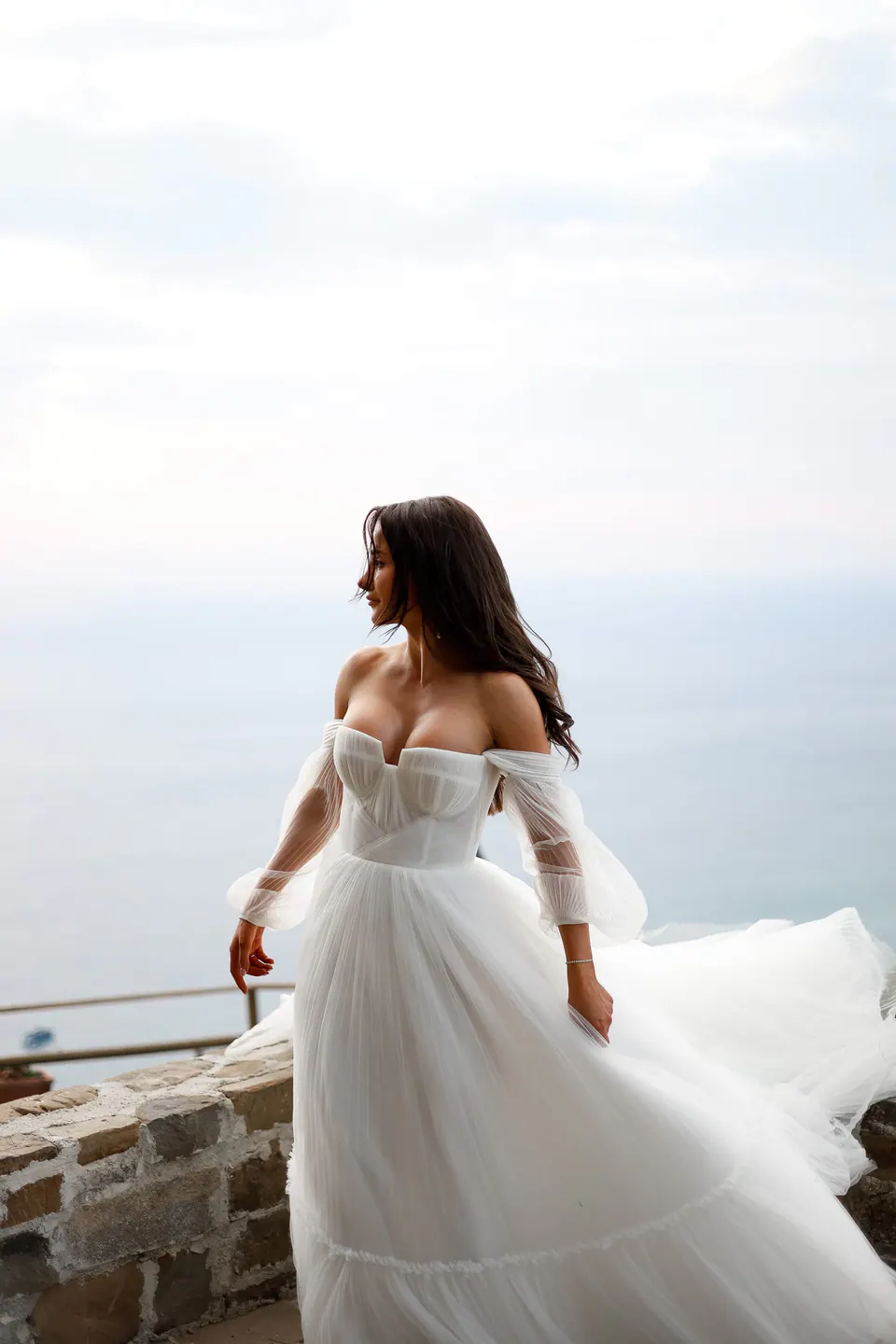 Die Braut im schulterfreien Kleid blickt in Santa Maria di Castellabate aufs Meer.
