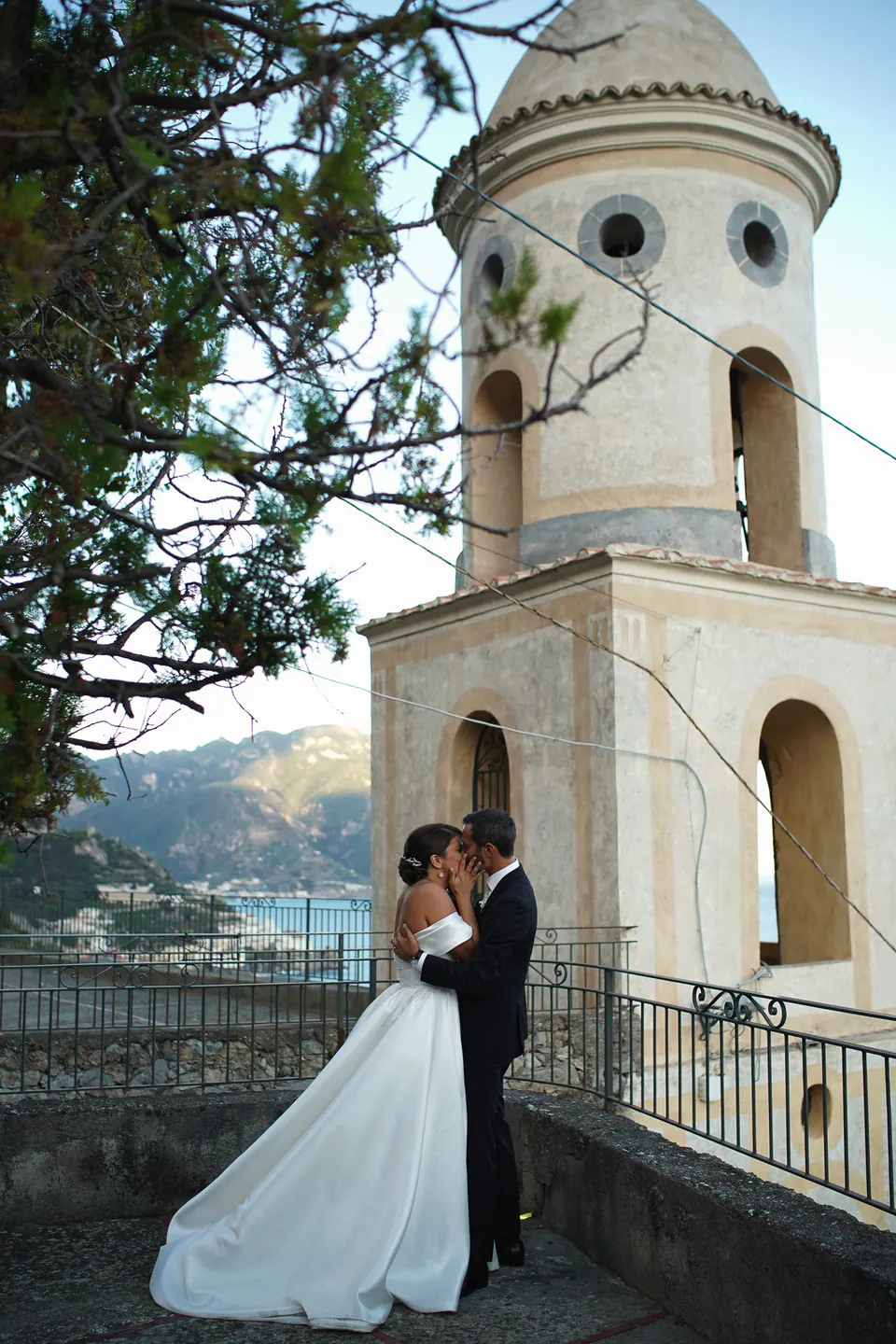 Bride by the bell tower, the coast behind her.