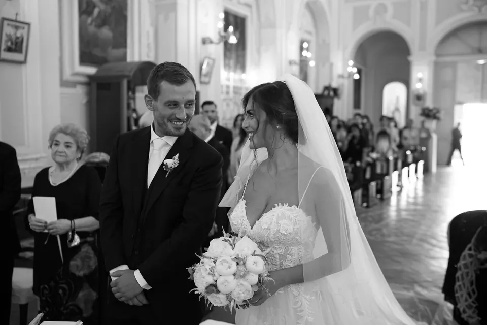 Sposi all'altare durante la cerimonia in chiesa, la famiglia guarda.