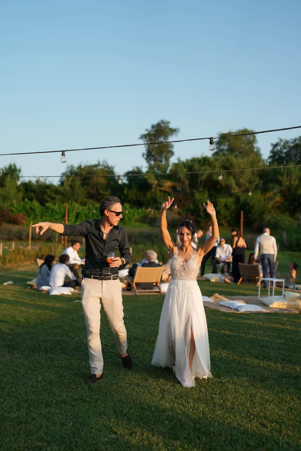 Bride and groom dancing on the lawn with their arms raised