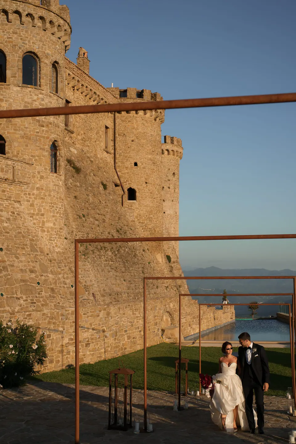 Sposi sotto le mura del castello al tramonto, la torre rotonda sopra di loro.