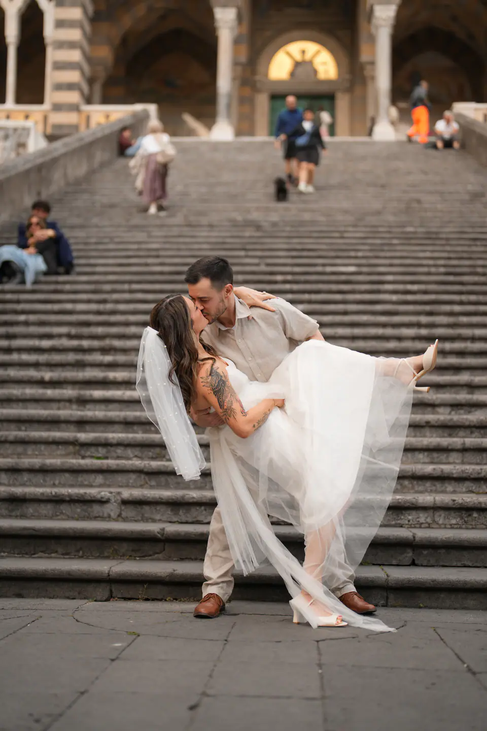 Groom carrying the bride down the steps of Amalfi Cathedral.