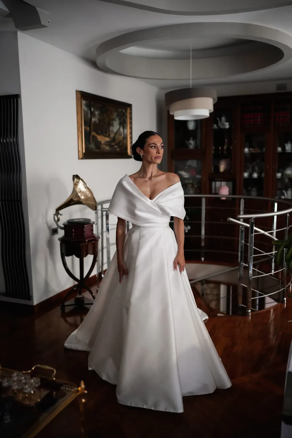 Sposa in piedi nel soggiorno di casa con l'abito dalla gonna ampia.