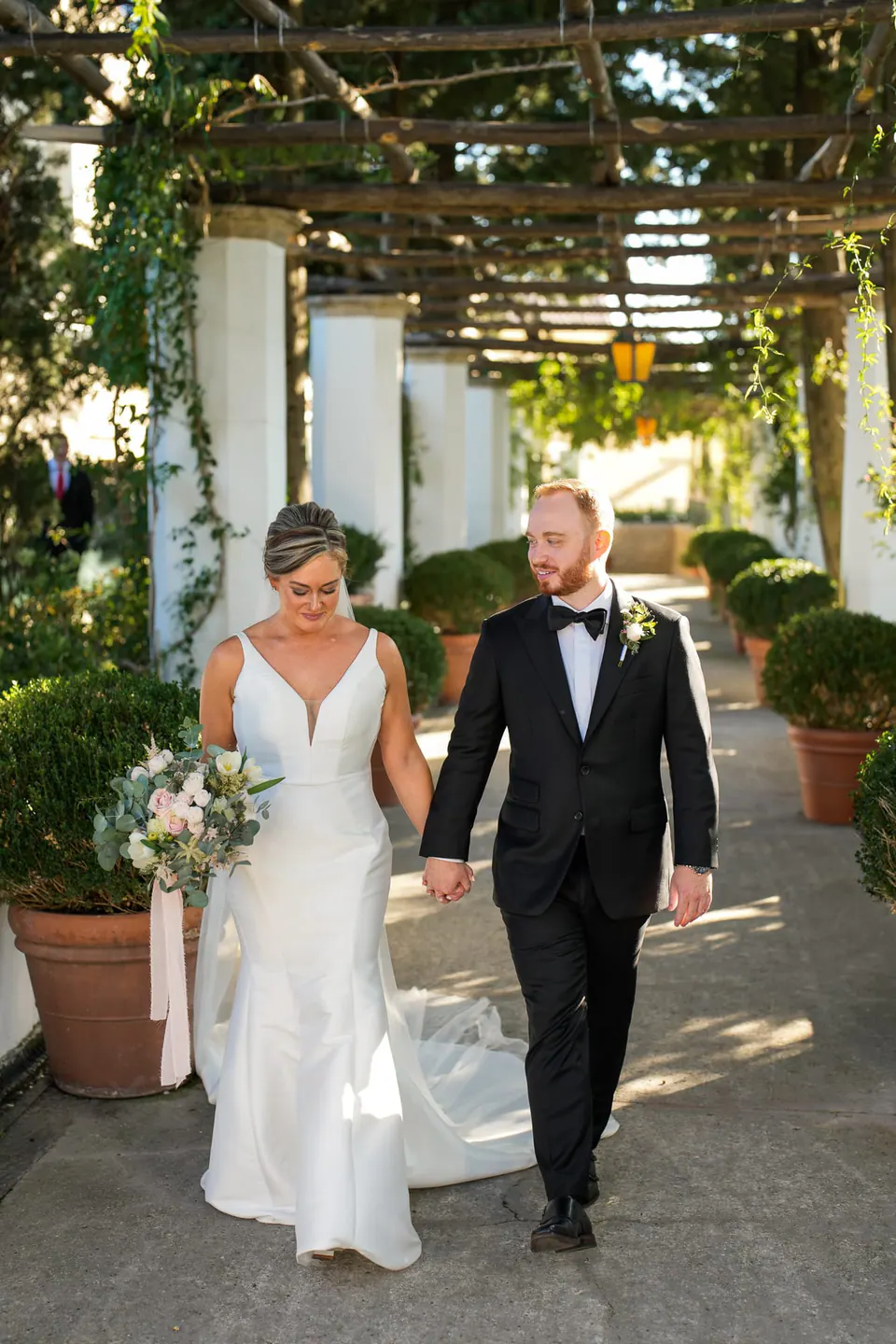 Bride and groom walking under the vine-covered pergola at the Belmond Hotel Caruso