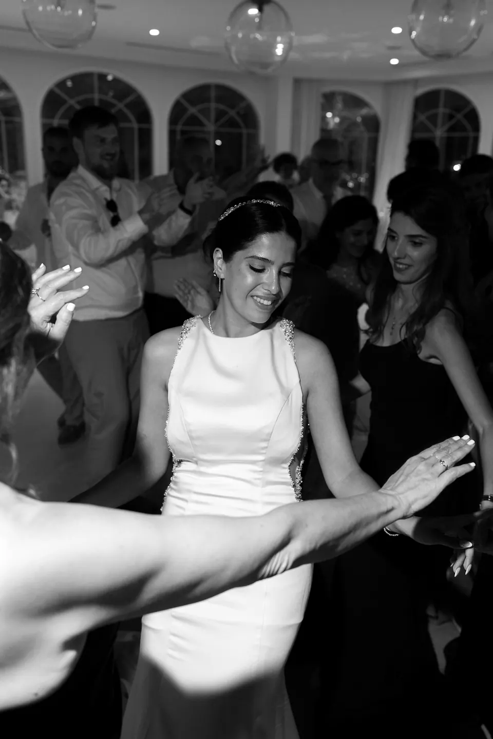 La mariée danse parmi les invités dans une robe dos nu à col américain, en noir et blanc.