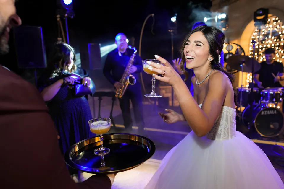 Bride dancing joyfully beneath twinkling blue lights, vibrant celebration moment at Tenuta San Domenico wedding reception.