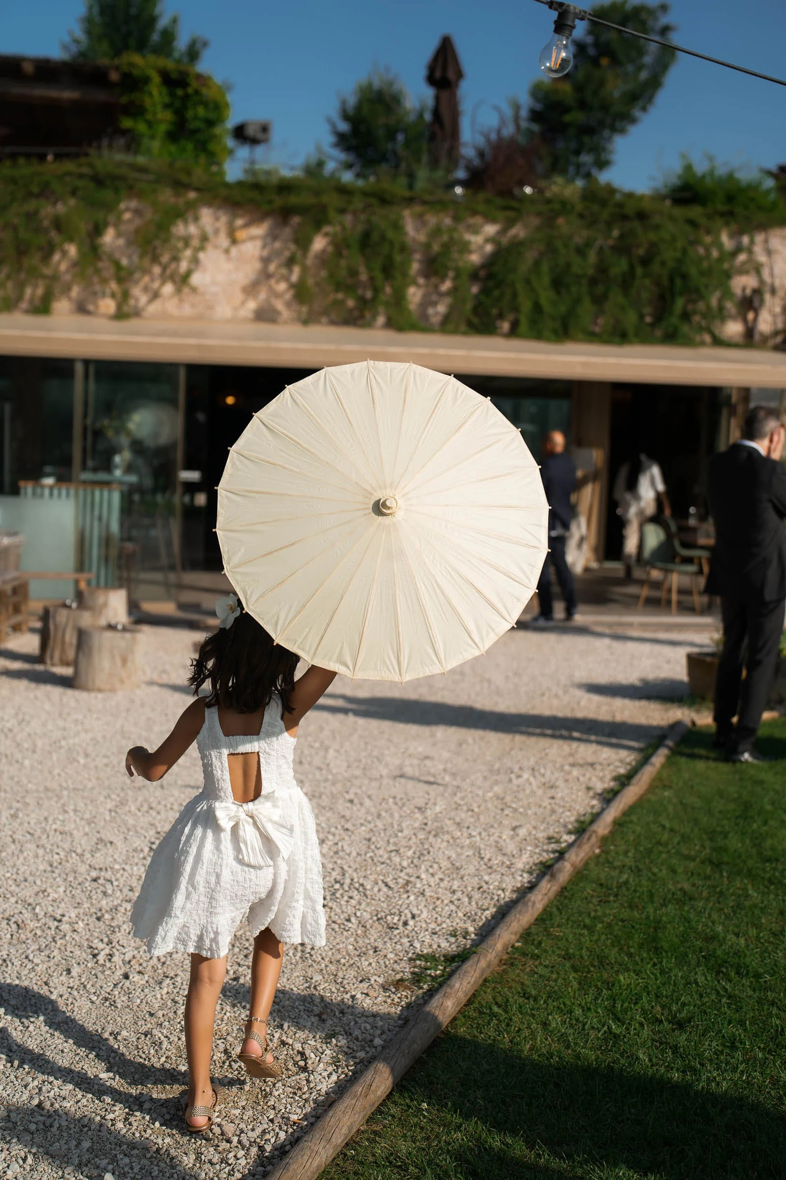 Guest with a white parasol walking along the gravel path at Borgo degli Antichi Orti.