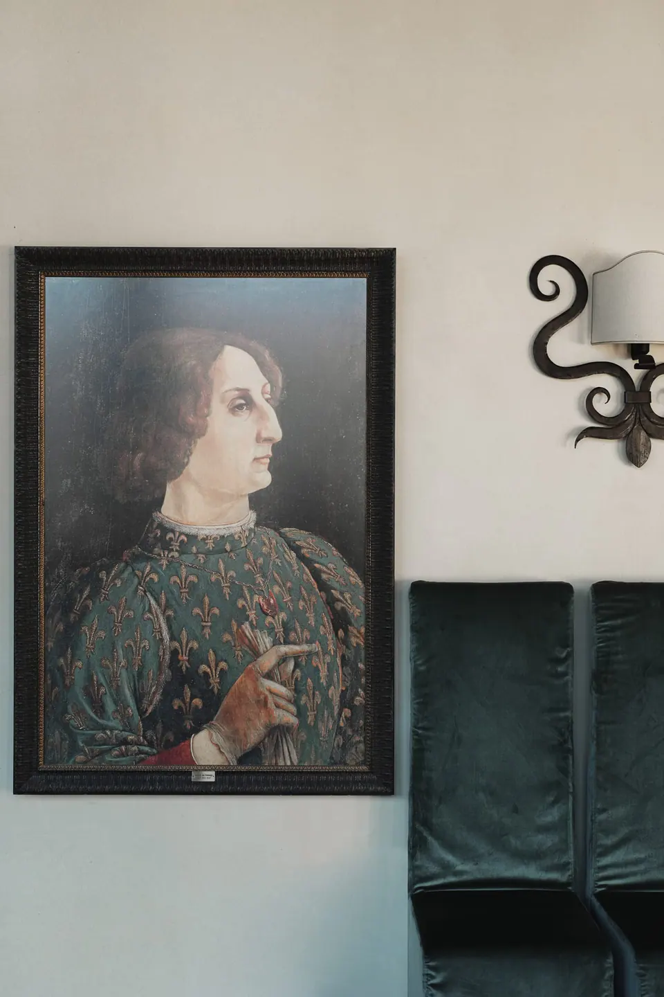 Gemaltes Porträt im Renaissancestil und schmiedeeiserne Wandleuchte an der Burgmauer.