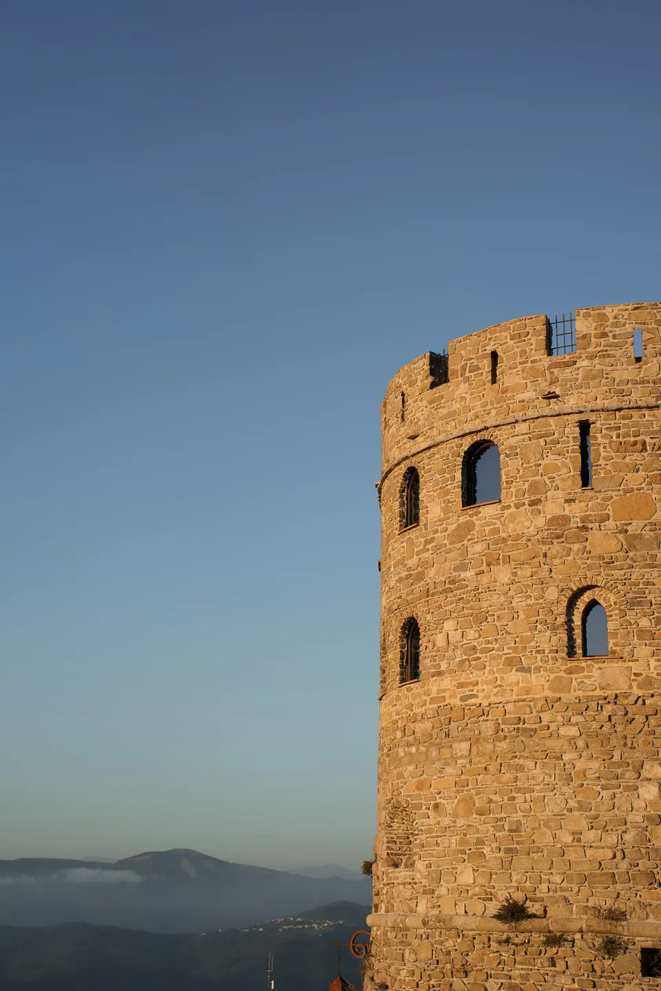 La torre rotonda medievale del Castello di Rocca Cilento contro il cielo limpido della sera.