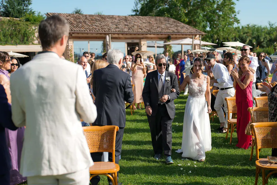 Bride walking up the aisle among the guests on the lawn