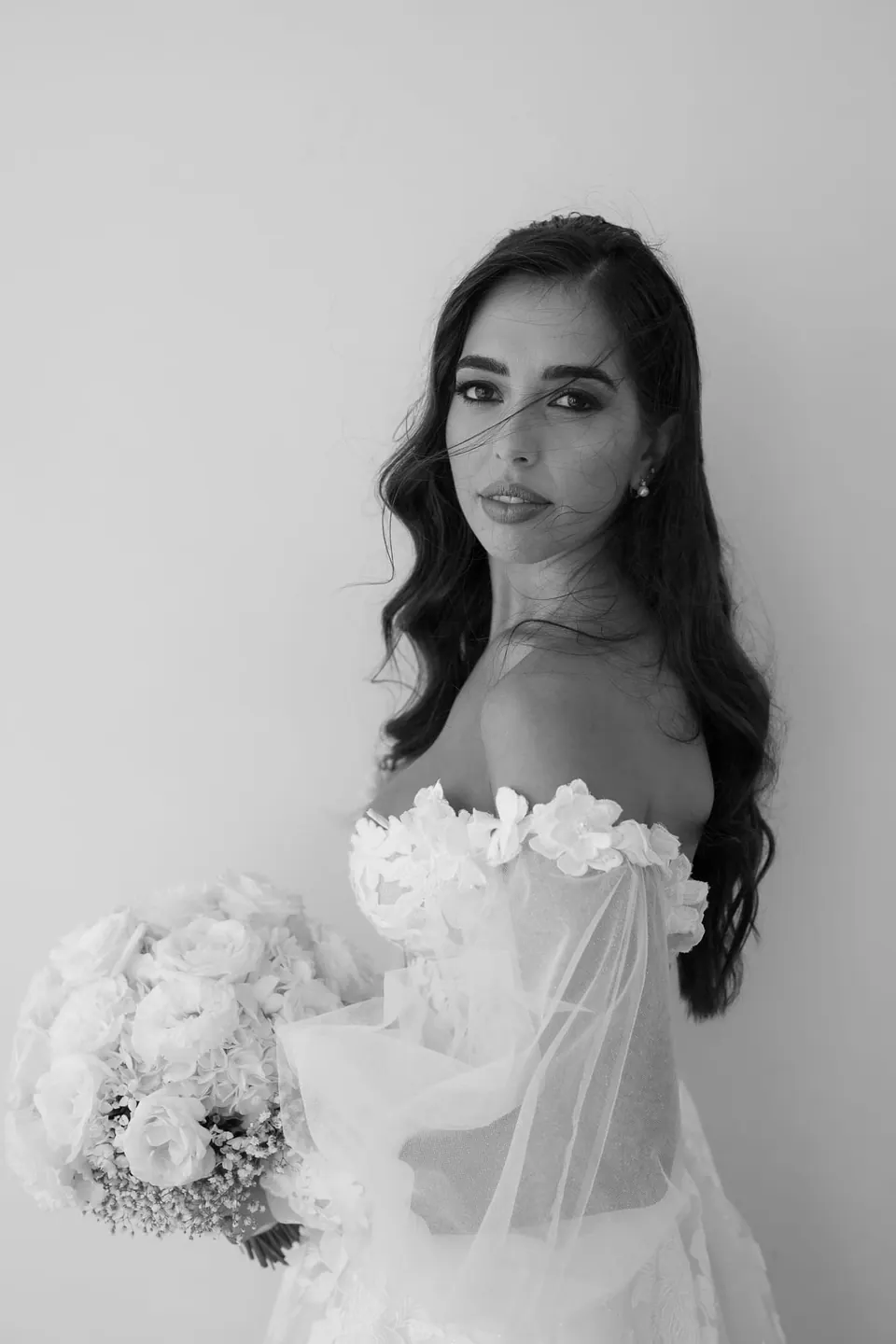 Black and white portrait of the bride with her bouquet of white roses.