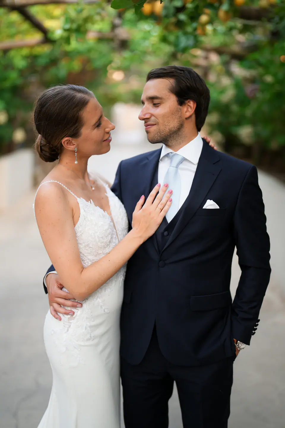 Bride resting her hand on the groom's chest under the lemons.