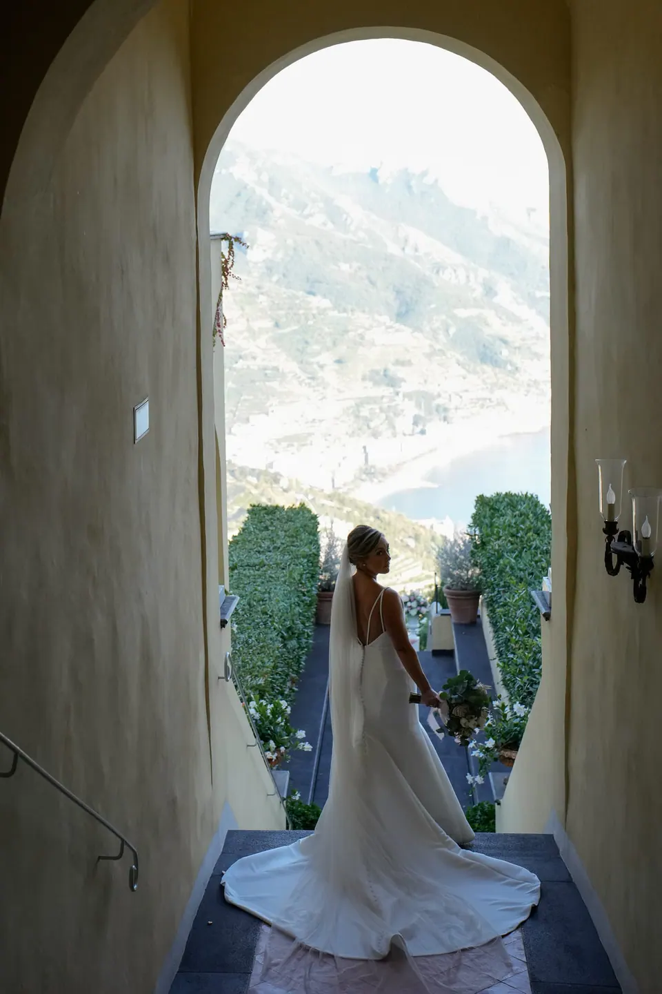 Bride seen from behind in an arched doorway, the coast beyond