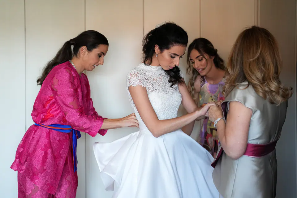 Women in pink and lilac adjusting the bride's dress