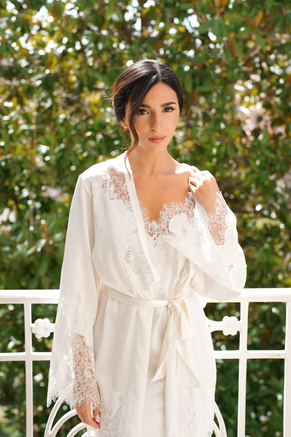 Bride leaning on a white balustrade, smiling softly in the afternoon sunlight at Tenuta San Domenico.