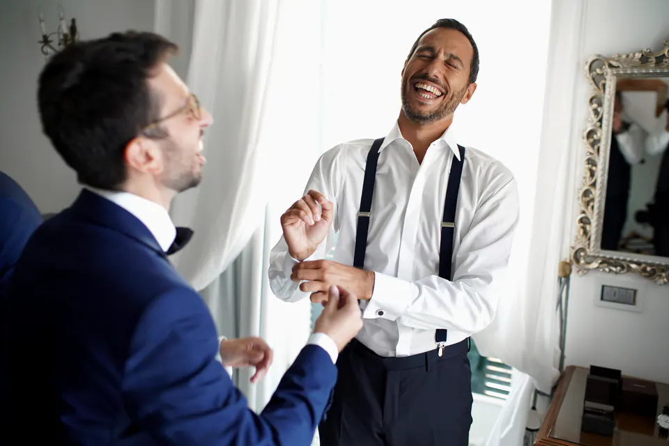 Groom laughing with his groomsmen during preparations, candid storytelling shot.