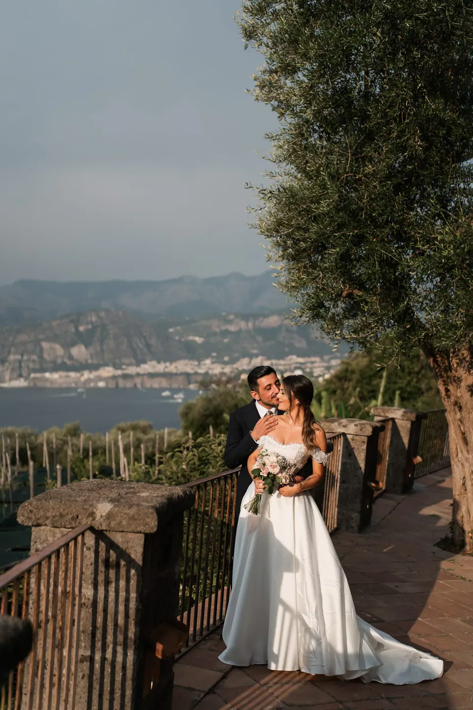 Bride and groom on a wooden terrace looking across the Bay of Sorrento