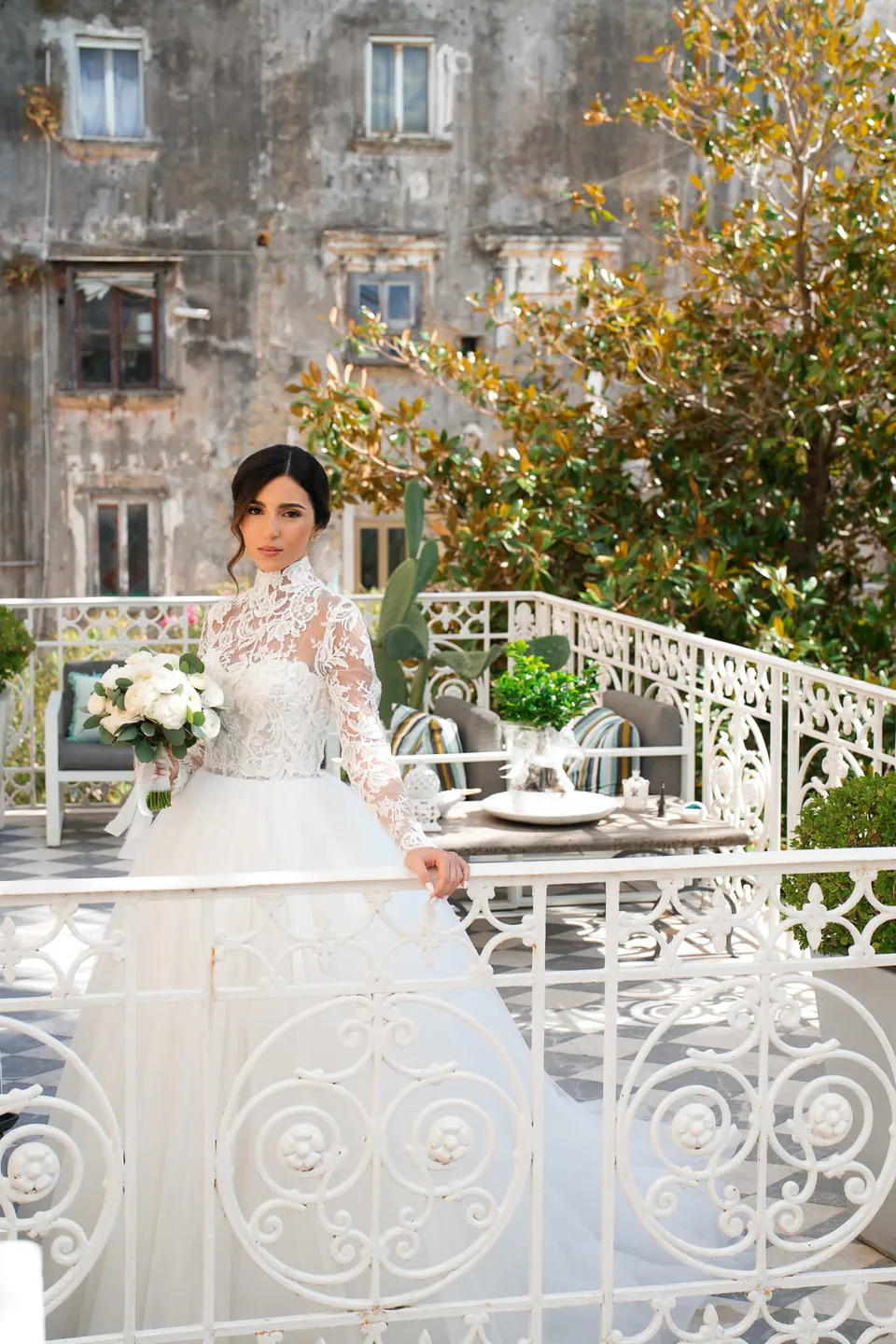 Bride on a terrace with a white railing, an old palazzo behind