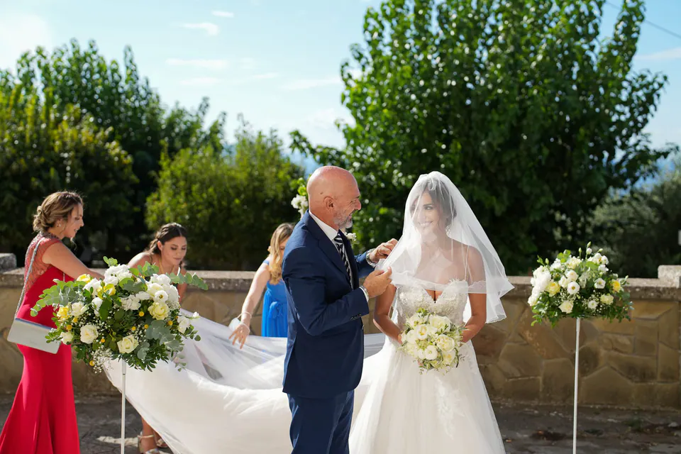 Il papà accompagna la sposa in chiesa, le damigelle con i bouquet accanto a loro.