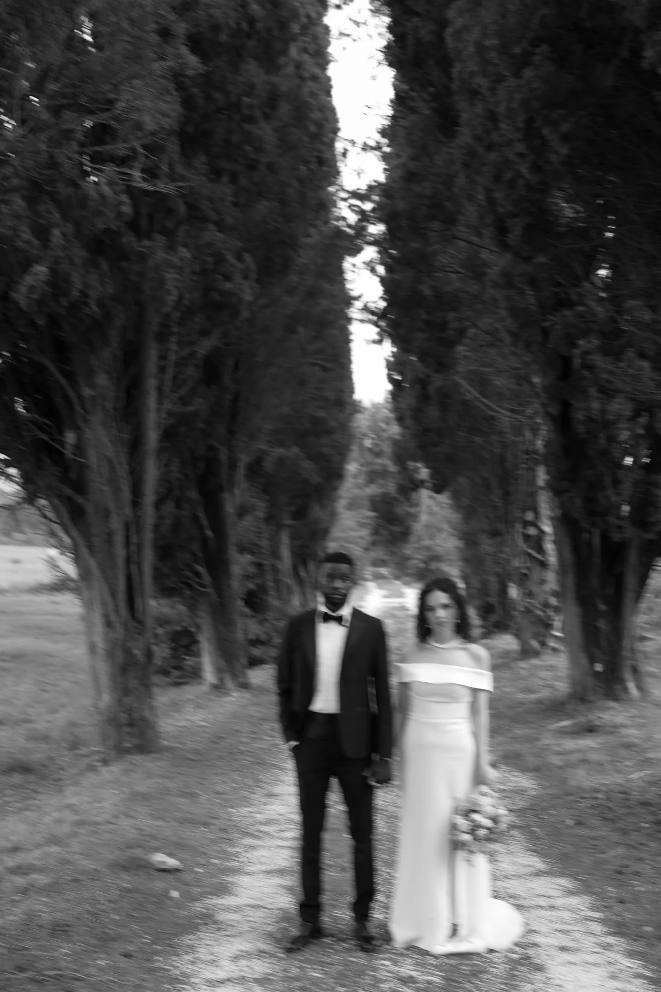 Sposi insieme lungo un viale alberato durante un ritratto editoriale di destination wedding in Italia.