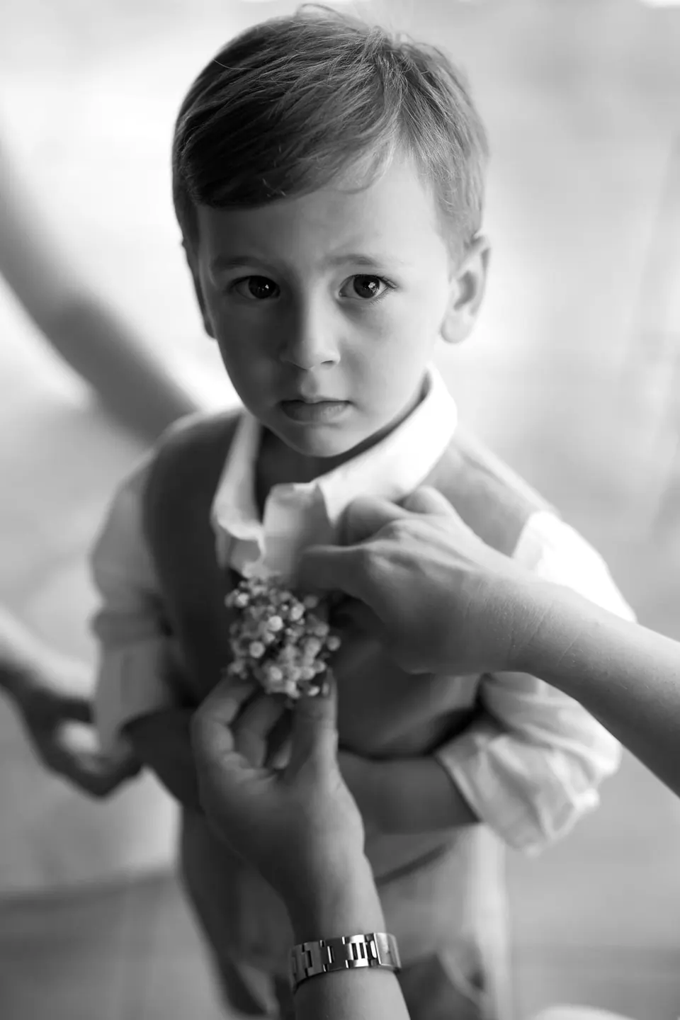 Black and white photo of a little boy having his boutonniere pinned