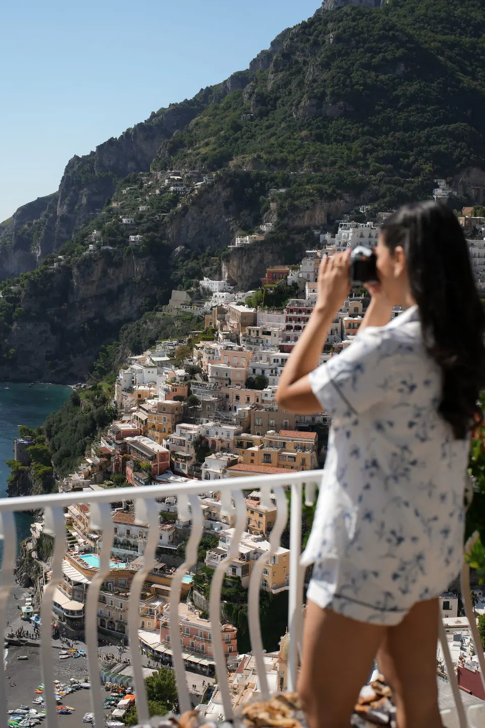 Bridesmaid in floral pyjamas taking a photo of the view of Positano.