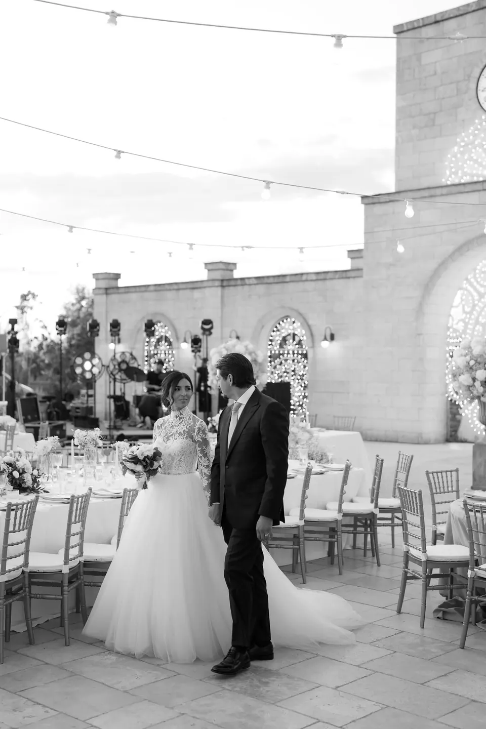Black and white photo of bride and groom in the courtyard among the tables