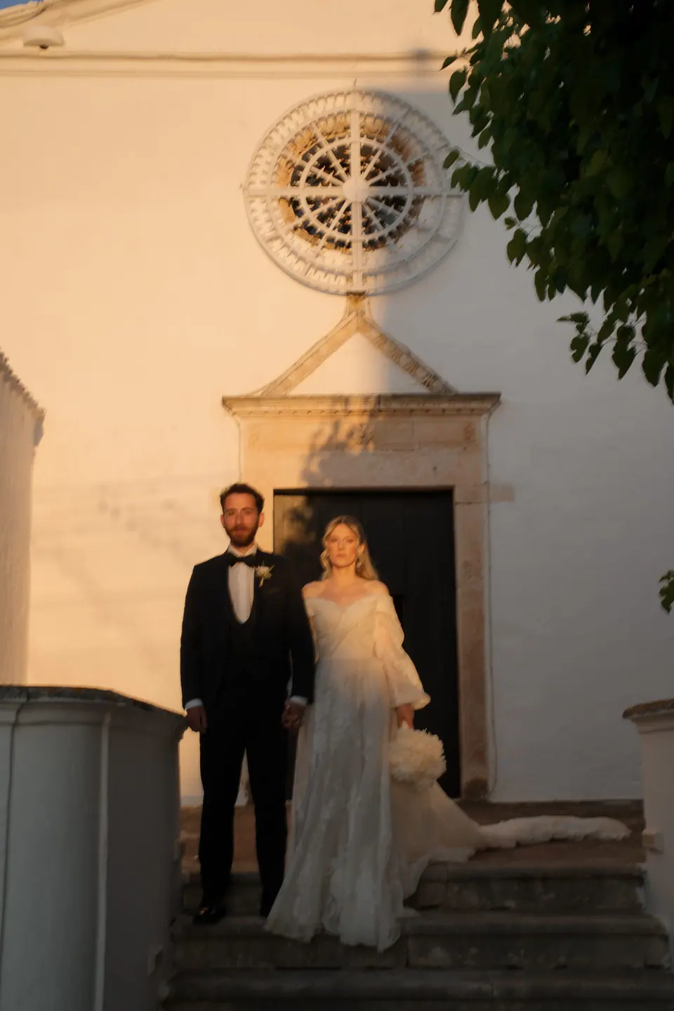 Los novios en la puerta de la iglesia de piedra al anochecer.