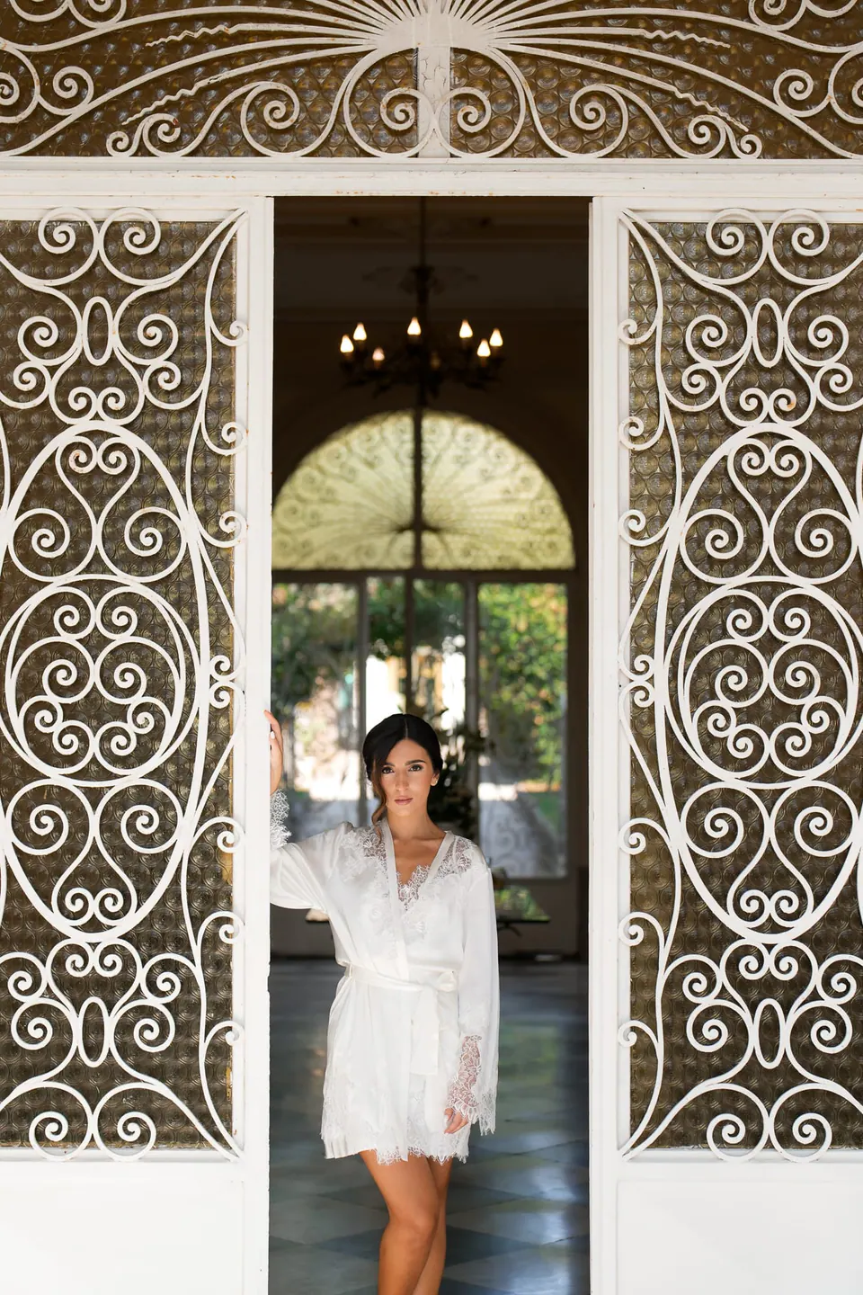 Bride in her robe in a doorway with ornate ironwork