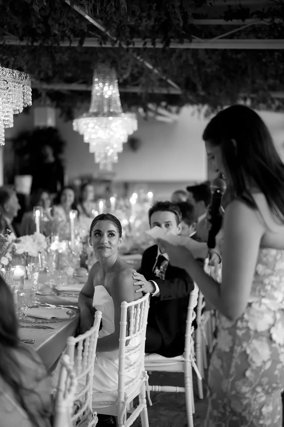 Black and white photo of a bridesmaid giving a speech at dinner.