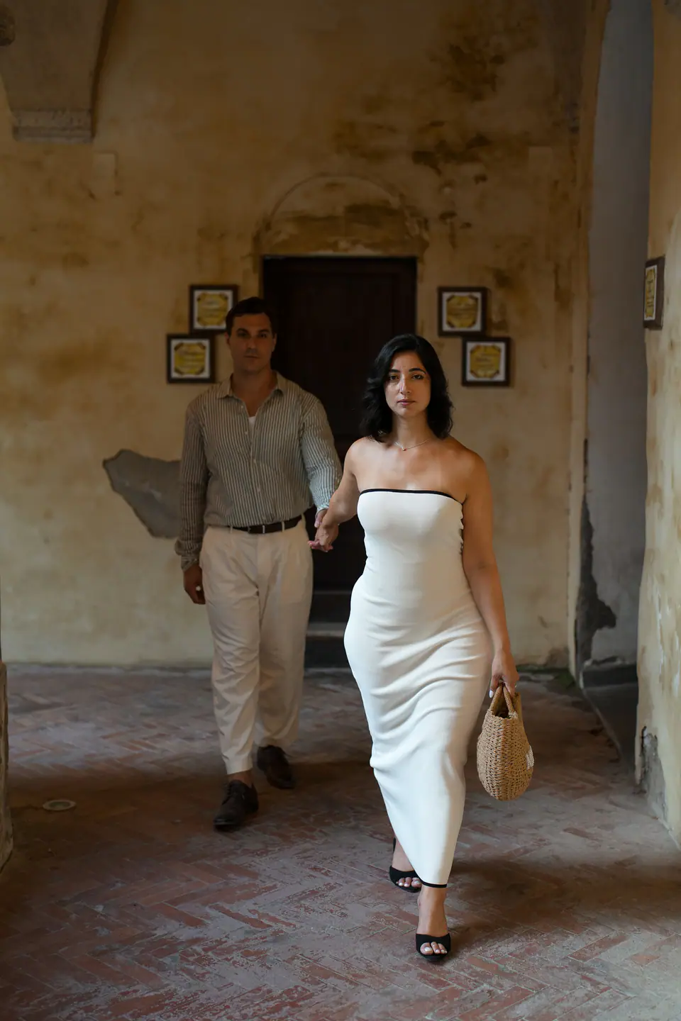 Couple walking through a doorway in a sunlit courtyard.