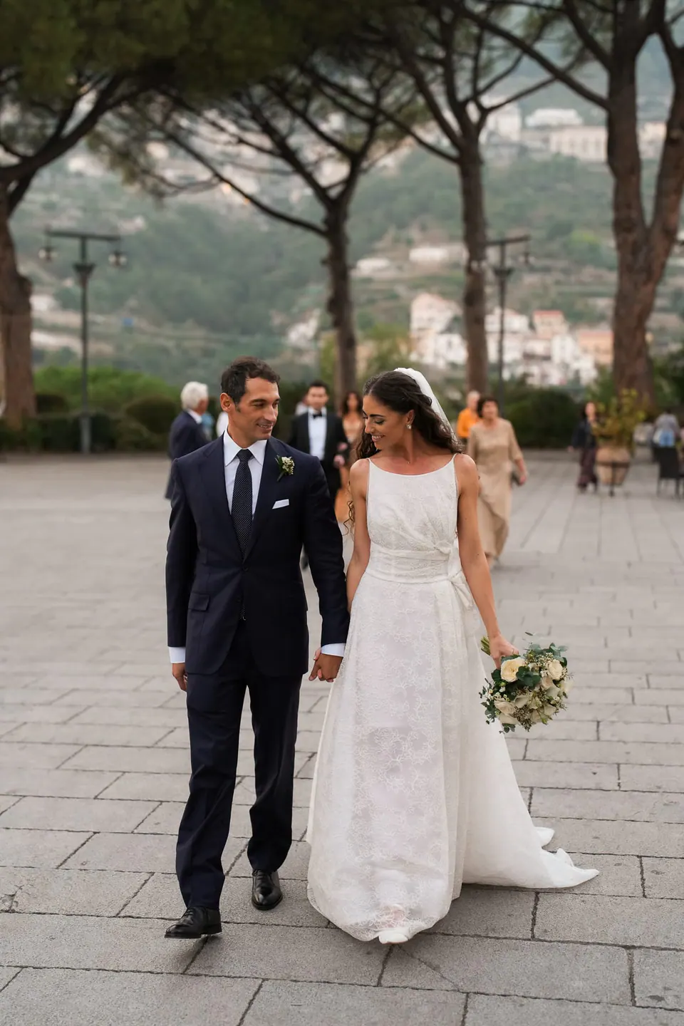 Bride and groom walking in the gardens of Villa Cimbrone beneath umbrella pines.
