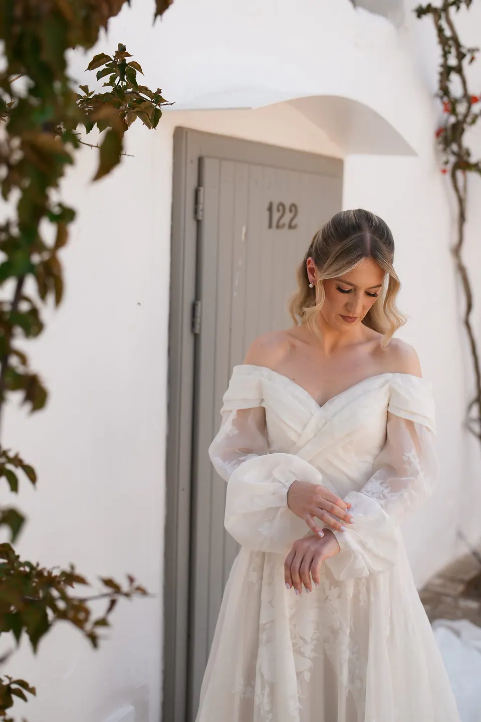 La novia sonríe delante de muros de piedra blanca.