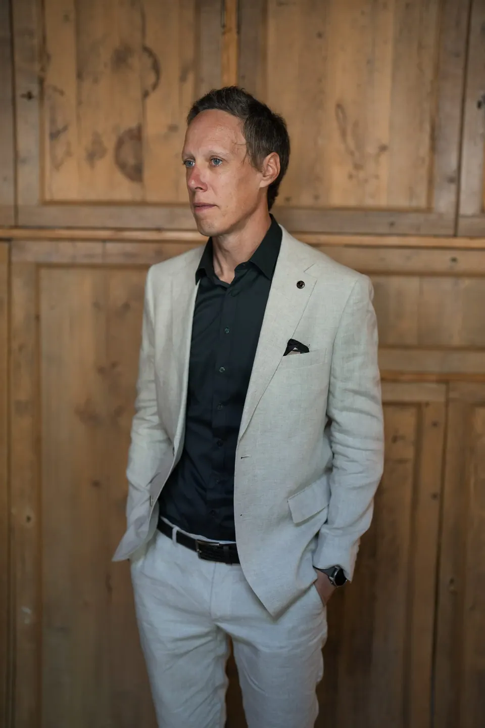 A guest in a light suit against a wooden wall