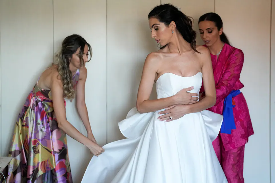Women adjusting the bride's strapless dress