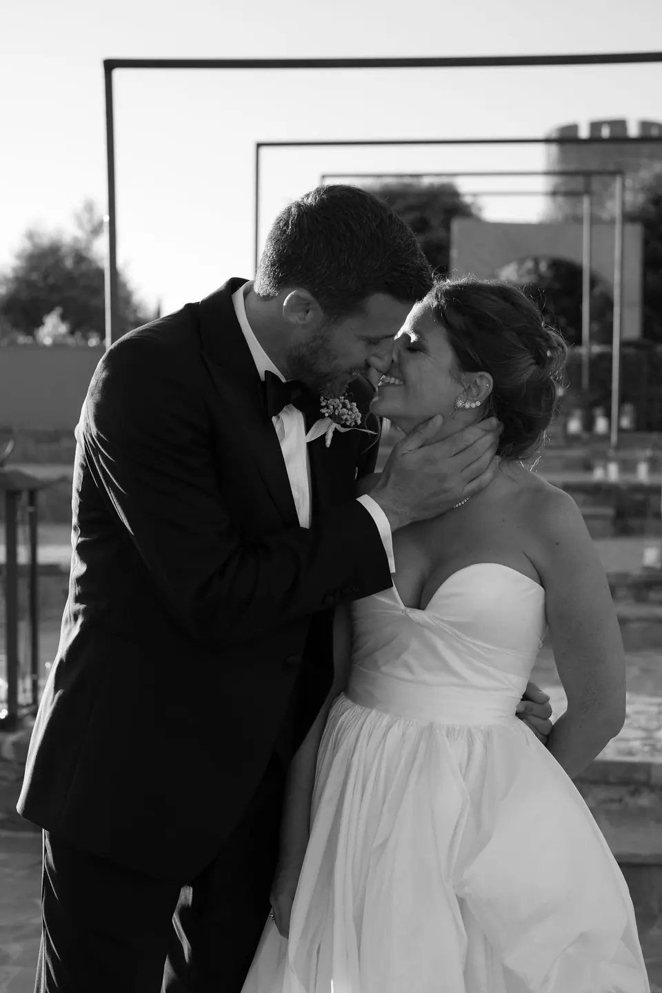 Foto in bianco e nero dello sposo che bacia la sposa.