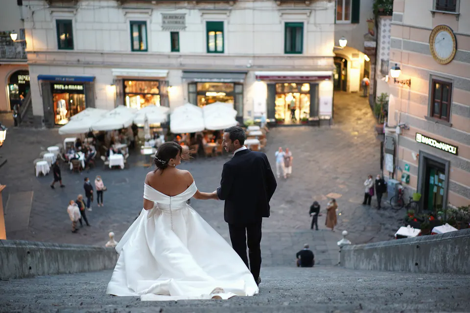 Bride and groom on the cathedral steps looking over Piazza Duomo in Amalfi at dusk.