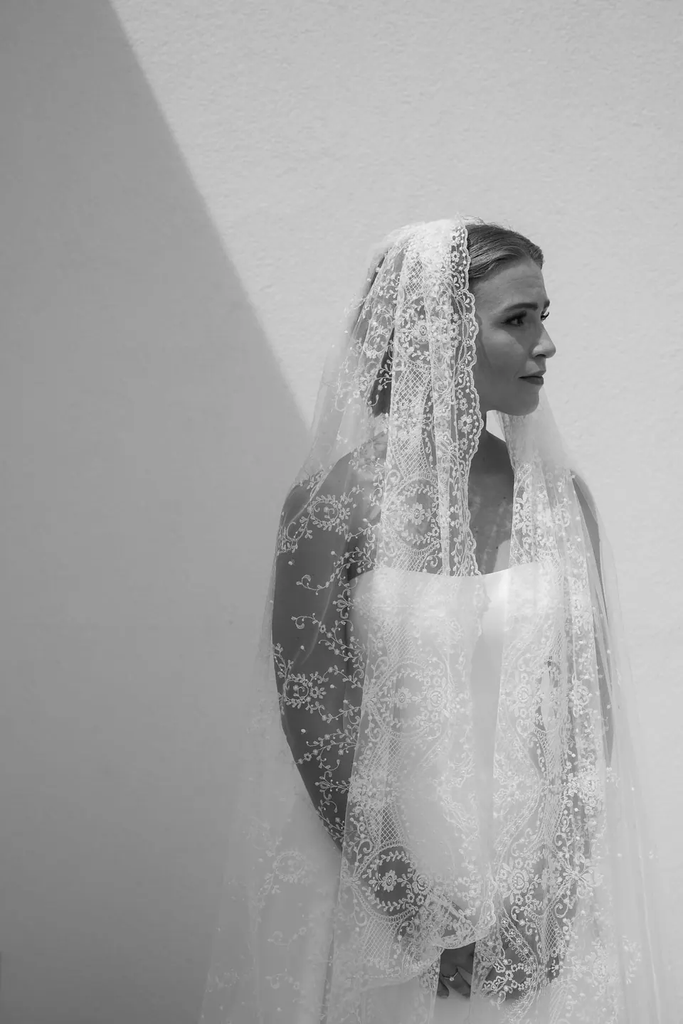 Schwarzweißporträt der Braut unter einer langen Spitzenmantilla.